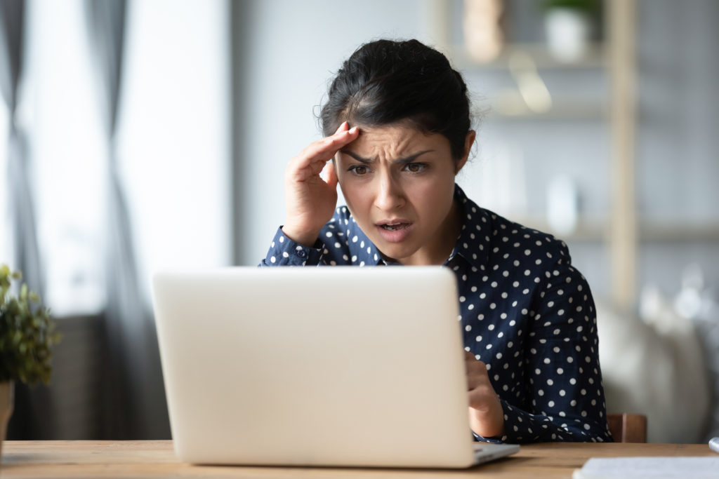 woman sitting in front of a laptop getting bad news